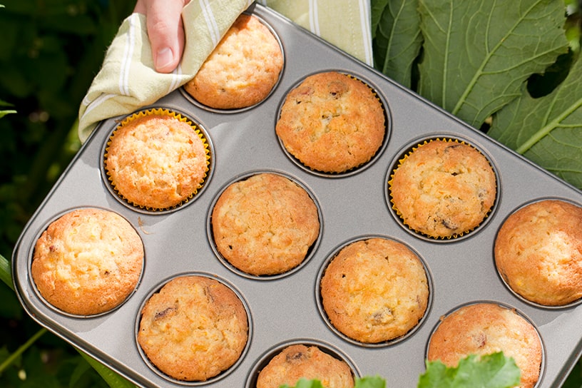 Iemand houdt courgettemuffins in een muffinbakvorm vast